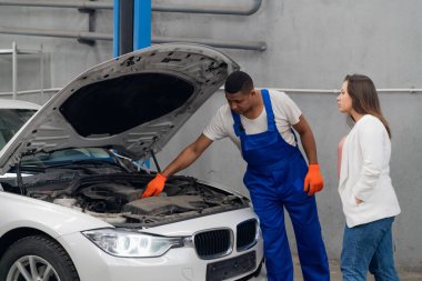 Atölye çalışanı ve müşteri arabanın motorunu denetliyor