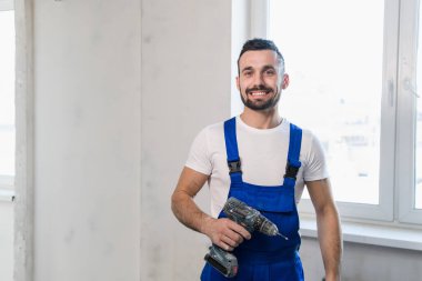 Yakışıklı işçi elinde matkap tutuyor.