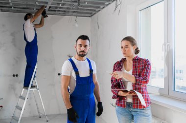 Müşteri üniformalı bir işçiyle konuşur ve not defterine not alır.