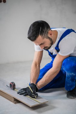 Mavi üniformalı işçi yapbozla kaplama kesiyor.