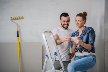 Erkek ve kız arkadaşı merdivende oturup telefondaki fotoğraflara bakıyorlar.