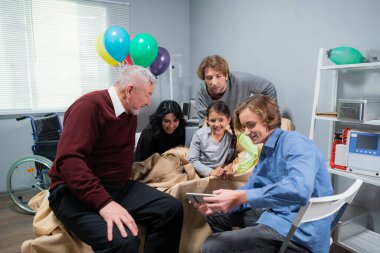 Küçük kızlarının hastane koğuşunda doğum gününü kutlayan bir aile.