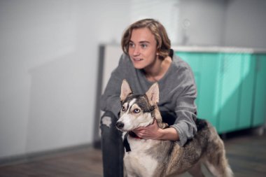 Evde bir kız ve iri bir köpek oynuyor.