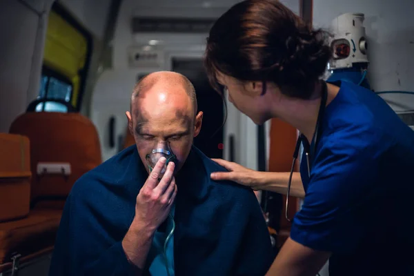 A medical worker talking to an injured man, trying to comfort him