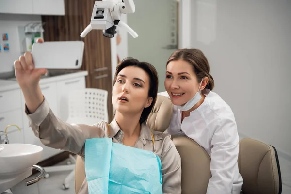 Una selfie inusual. Fotografía de una mujer joven tomando una selfie con su dentista después de su chequeo — Foto de Stock