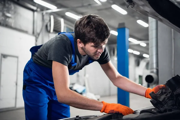 Mechanik w rękawiczkach zastępuje silnik samochodu. — Zdjęcie stockowe