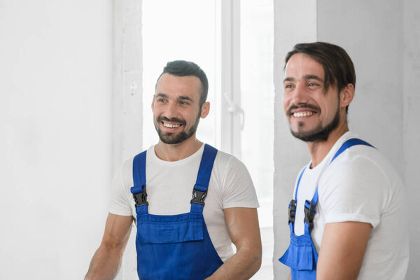 Two men in blue overalls. They are smiling