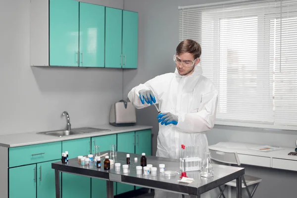 Um jovem cientista que trabalha com materiais líquidos em tubos de ensaio no laboratório — Fotografia de Stock
