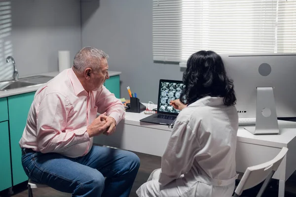 Paciente sênior ouvindo os médicos explicarem o que ela vê no raio-x — Fotografia de Stock