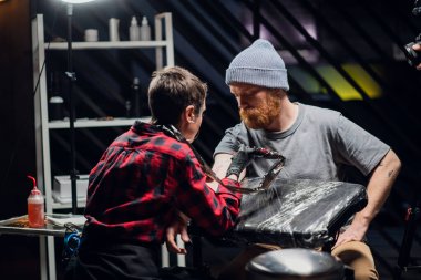 Dövme salonunun müşterisine göre genç bir sanatçı koluna sopa ve dürtme metodu kullanarak acısız bir dövme yapıyor..