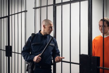 Asyalı bir hapishanede üniformalı bir kahya mahkumlarla birlikte hücrede bir akşam turu yapıyor.