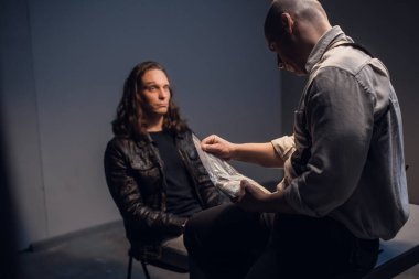 Sorgu odasında, kelepçeli bir şüpheli avukatsız bir polis ya da FBI dedektifi ile görüşüyor..