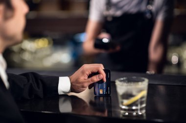 Adam barmene siparişin parasını kredi kartıyla ödüyor.