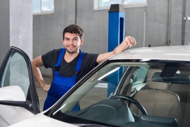 Bir tamirci arabanın yanında duruyor.