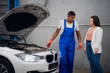 Araba servisi çalışanı müşteriye arabanın motorunu gösterir.
