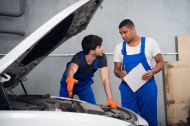 İki tamirci arabayı kontrol edip onarımları tartışacak.