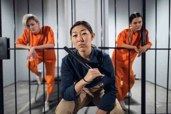 Портрет азіатського охоронця на тлі двох милих злочинців в клітинах — стокове фото