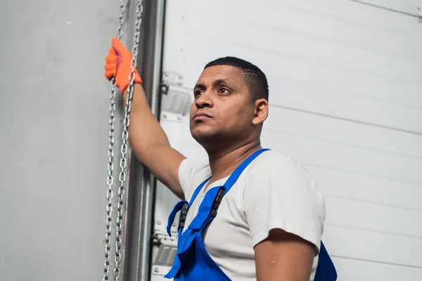 Mecânico em macacão fica perto da porta da garagem — Fotografia de Stock