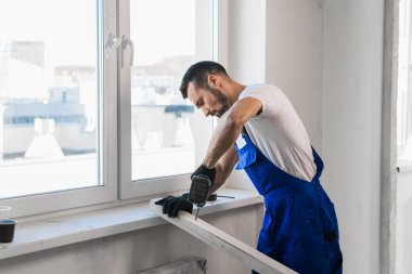 Tulumlu müteahhit kollarını göğsünün üzerine kavuşturmuş.