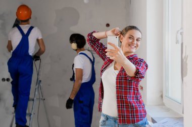 Kadın, iş yerindeki genel işçinin arka planında selfie çekiyor.