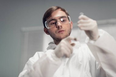 Plastik bir tüpe kimyasal enjekte eden bir bilim adamının yakın plan portresi.