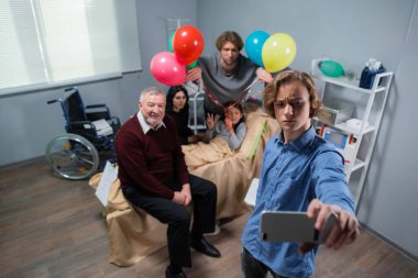 Bir aile, kötü bir kazadan sonra rehabilitasyonda kalan doğum günü kızıyla selfie çekiyor.