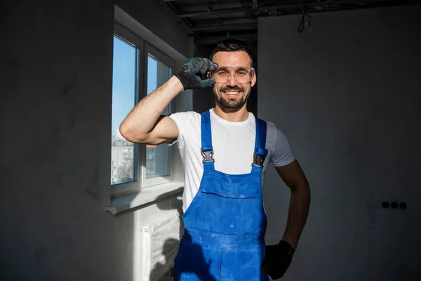 파란 작업복과 고글을 쓴 노동자가 웃으며 — 스톡 사진
