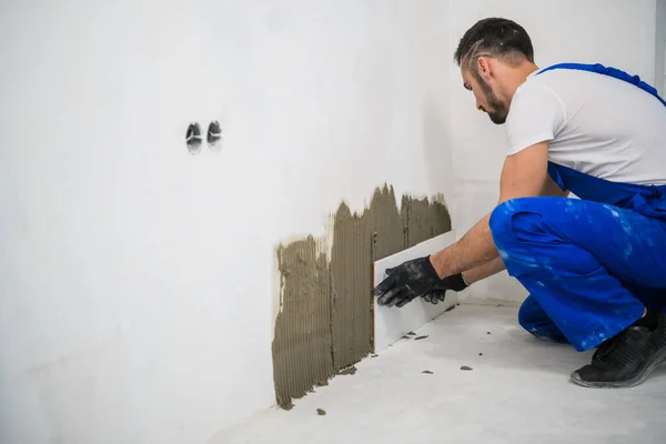 Man in overall zet tegels op de badkamermuur — Stockfoto