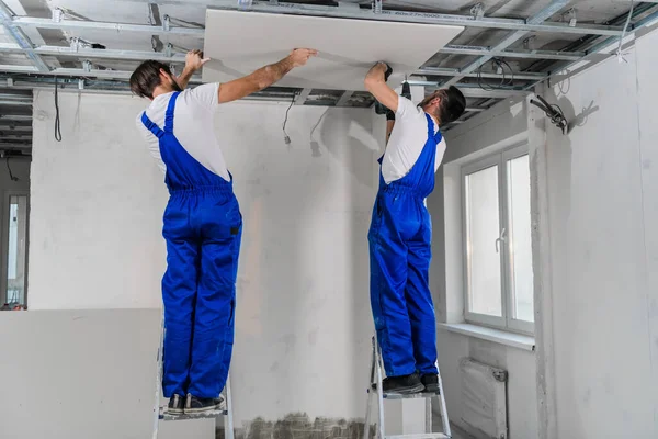 Handymen are assembling a plasterboard ceiling using a drill — Stock Photo, Image