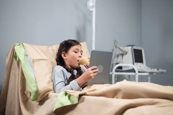 Paciente femenina adolescente que se relaja en la cama del hospital con la tableta digital — Foto de Stock