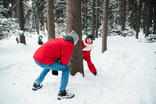 No inverno, um jovem pai joga catch-up com seu filho na floresta entre as árvores — Fotografia de Stock