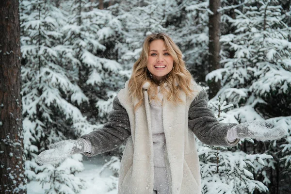 An incredibly joyful beauty walks through a winter fairy-tale forest. Throws up flakes of snow. Portrait with depth of field. — Stock Photo, Image