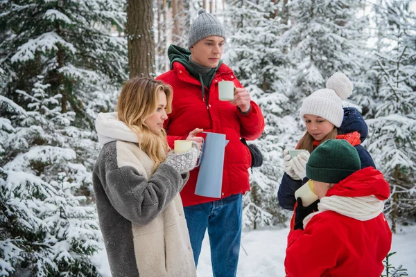 Зимняя сказка для молодой семьи с детьми, мальчиком и девочкой, гуляющей по лесу в выходной день. Снегопад и горячий чай в термосе. — стоковое фото