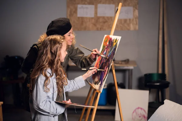 Молода жінка-художниця вчить студентку малювати в студії. Приватний урок . — стокове фото