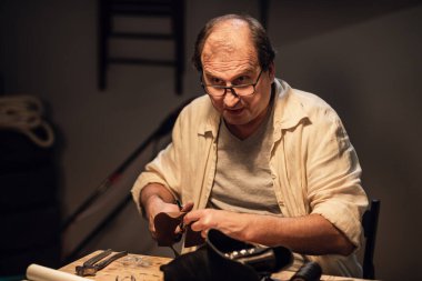 Eski bir ayakkabıcı deriden ayakkabı yapar ve atölyedeki çıraklarının sorularını cevaplar..