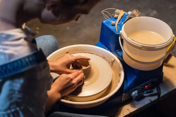 Красивые руки молодой девушки, испачканные глиной при моделировании горшка на гончарном круге в мастерской. — стоковое фото