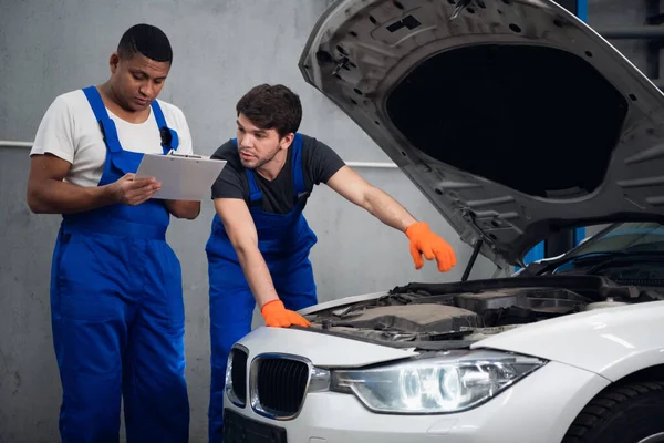 Reparatören samråder med en kollega om en bilreparation — Stockfoto