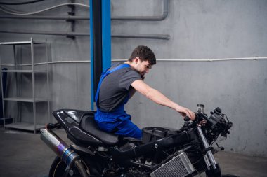 Bir makinist bisiklette oturup müşterisini arıyor.