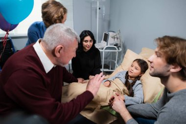 Bir aile, hastaneye ziyaretleri sırasında küçük kızı teselli ediyor.