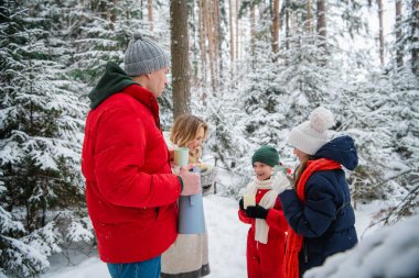 Çocukları olan genç ve güzel bir çift, yeni yıl boyunca ya da Noel tatillerinde muhteşem bir kış ormanında yürürler. Termostan çıkan sıcak çayla ısınıyorlar..