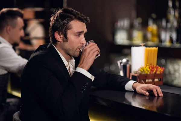 Молодий чоловік п'є воду з лимоном в барі в нічному клубі — стокове фото