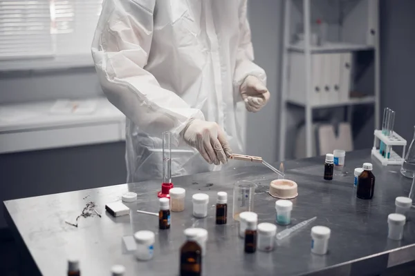 Um cientista com as mãos enluvadas aquecendo uma vara na mesa do laboratório — Fotografia de Stock