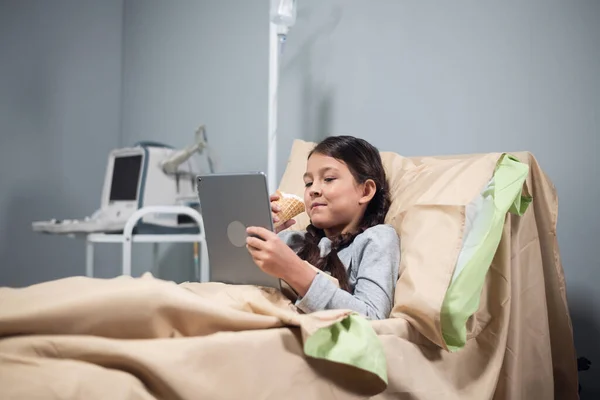 Paciente femenina adolescente que se relaja en la cama del hospital con la tableta digital — Foto de Stock