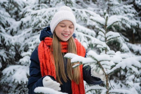 A beautiful schoolgirl spends her holidays in a country house and walks through a winter forest with firs, pines and snow. — Stock Photo, Image