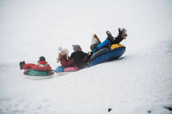 Os pais compraram seus filhos tubulação e agora toda a família passeio para baixo o deslizamento de gelo — Fotografia de Stock