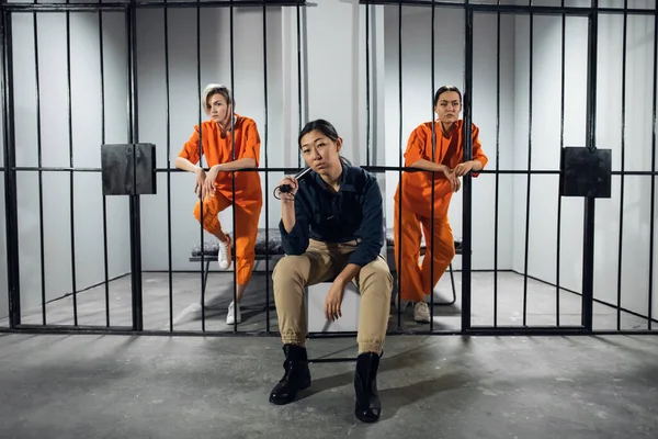 Три дівчини в жіночій в'язниці, охоронець і два злочинці позують на фото — стокове фото