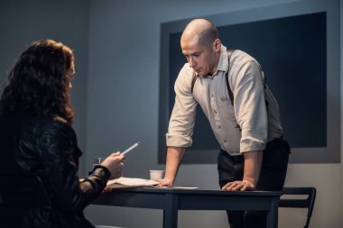 Dedektif şüpheliyi dava materyalleriyle tanıştırır ve imzalamasını ister.