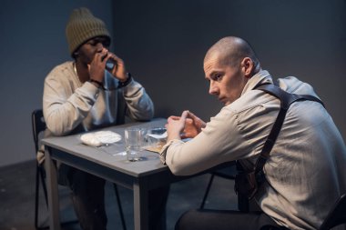 Karakolda sorgulanan şapkalı siyah bir şüpheli başka bir yerde olduğunu iddia ediyor.