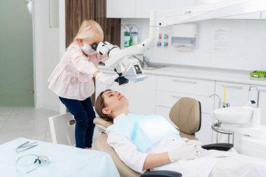 Pediatrik dişçi muayenesi sırasında diş malzemeleriyle oynayan bir çocuk.