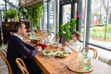 Bir çocuk babasının aletle fotoğrafını çekiyor.